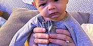 Cohen joined the competition — help win amazing prizes! baby, infant, hands, rings, onesie, blanket, cushion, indoor, person, face, expression, serious, home, soft_lighting, furniture, portrait, child, newborn, cozy, adult_hands