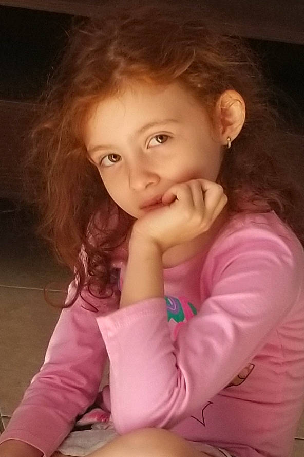 Anabella is registered to the contest to win money with this photo: beauty, brown_hair, cheek, child, child_model, chin, eye, face, finger, fun, hair, lip, mouth, nose, person, photography, pink, sitting, skin, smile