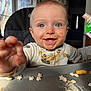baby, toddler, child, highchair, messy, food_smear, blue_eyes, smile, teeth, reaching_hand, tray, snack, cereal, puree_pouch, bib, indoor, window, portrait, closeup, happy