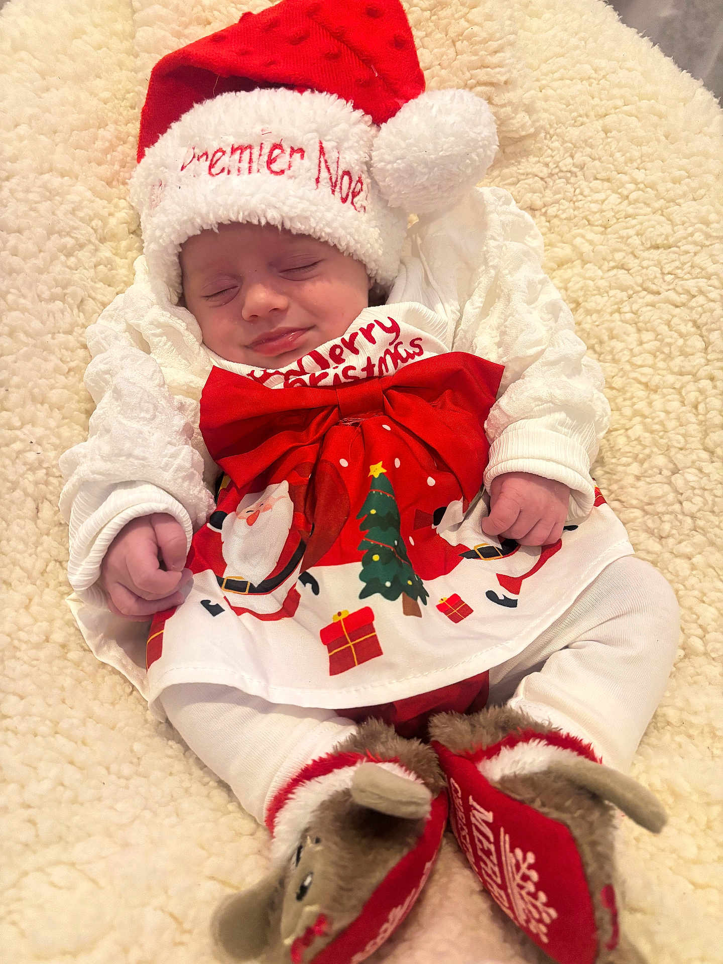 Anelya a rejoint le concours — aidez-le/la à gagner de superbes lots ! baby, sleeping, christmas_hat, christmas_clothing, red_bow, reindeer_slippers, blanket, festive, holiday, cute, infant, white_clothing, soft_texture, smiling, cozy, holiday_season, christmas_tree, gift_box, santa_claus, indoors