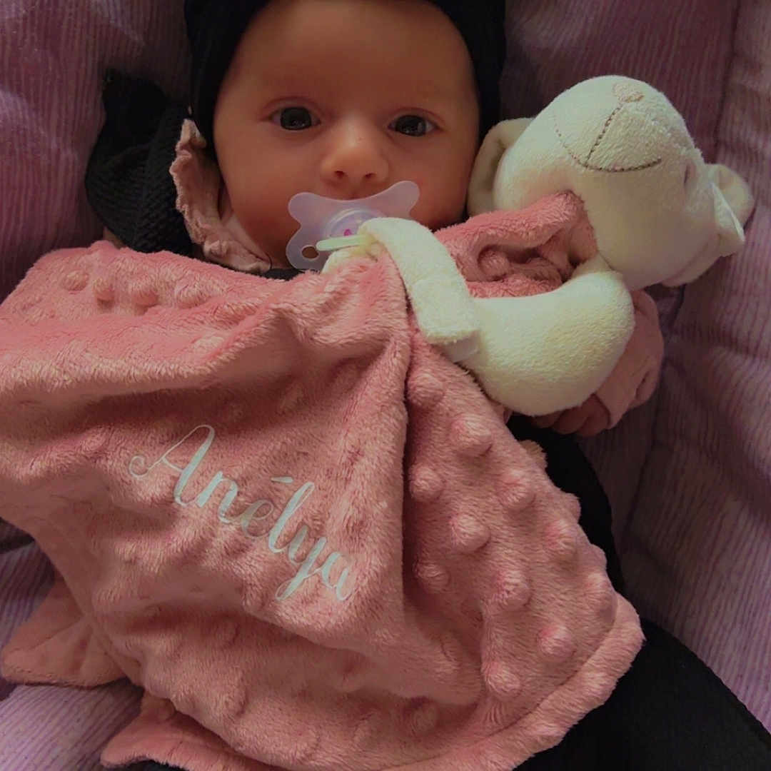 Anelya participe au concours pour gagner de l'argent avec cette photo : baby, black_clothing, blanket, child, closeup, comfort, cozy, cute, face, headband, indoors, infant, pacifier, pink_background, pink_blanket, portrait, rest, sleeping_area, soft_toy, stuffed_animal