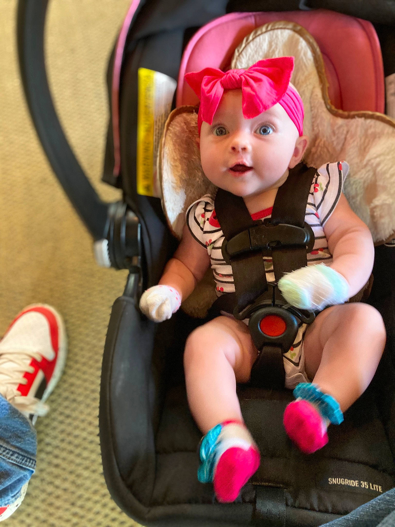 Pheobe is registered to the contest to win money with this photo: arm, baby, baby_carriage, baby_toddler_clothing, car_seat, chair, comfort, eye, fun, hand, headwear, lap, leg, person, pink, red, shoe, sneakers, tire, toddler