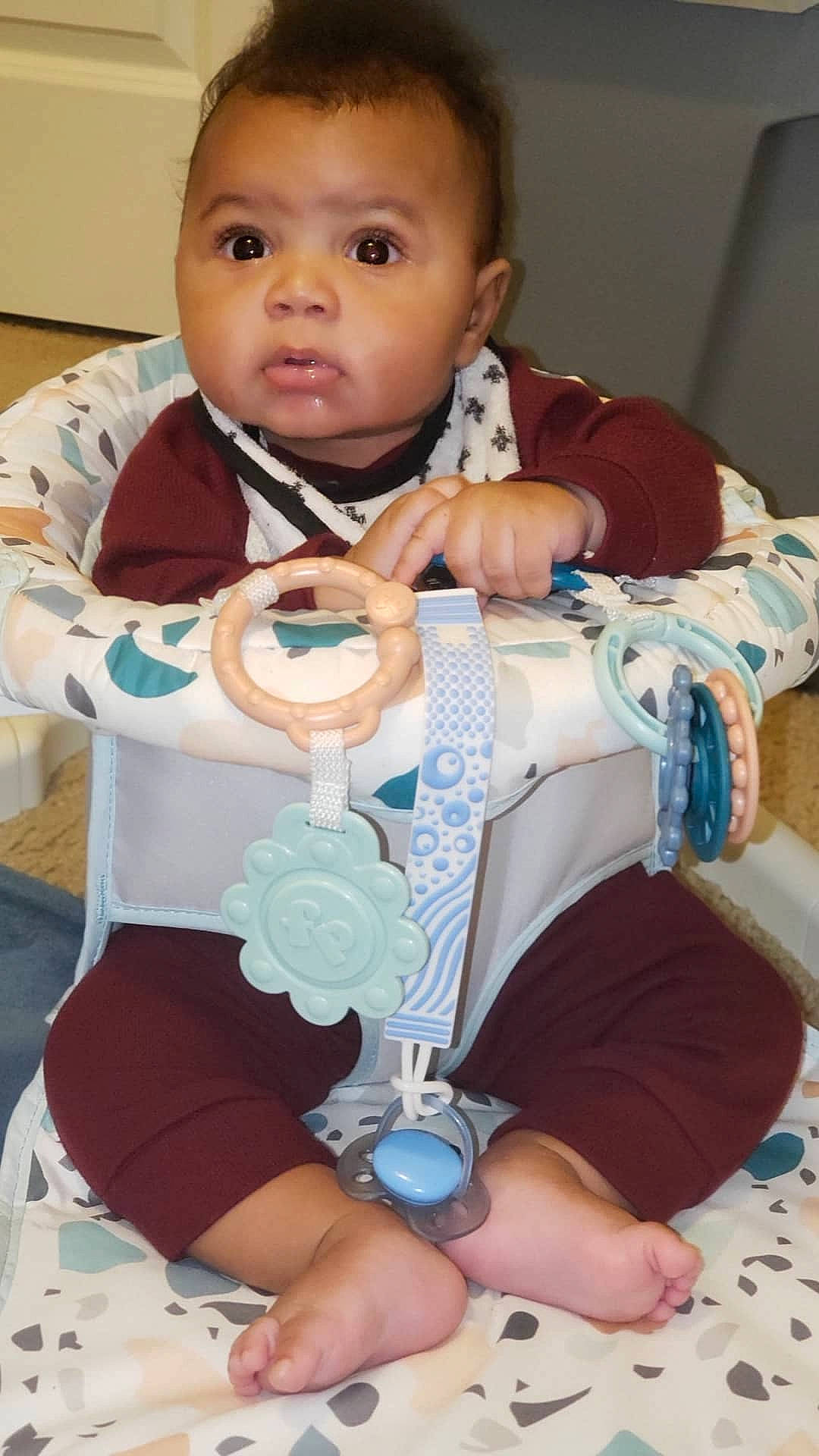 Royce is registered to the contest to win money with this photo: baby, baby_products, baby_toddler_clothing, bib, cheek, child, comfort, eye, facial_expression, finger, hand, health_care, linens, person, room, service, sitting, skin, sleeve, toddler