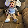 Imogen is registered to the contest to win money with this photo: baby, child, elephant_costume, costume, couch, brown_couch, indoor, cute, smiling, sitting, plush, face, headwear, clothing, footwear, home, young_child, infant, portrait, comfort