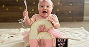 Imogen joined the competition — help win amazing prizes! baby, balloons, blanket, celebration, child, confetti, cute, decor, festive, girl, happy, headband, indoor, number_six, pink, sign, sitting, smiling, tassel_garland, wooden_wall