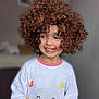 child, curly_hair, smiling, pajamas, indoor, cute, happy, face, person, childhood, playful, curly_wig, long_sleeve, white_clothing, pink_trim, bunny_design, cheerful, portrait, young, fun