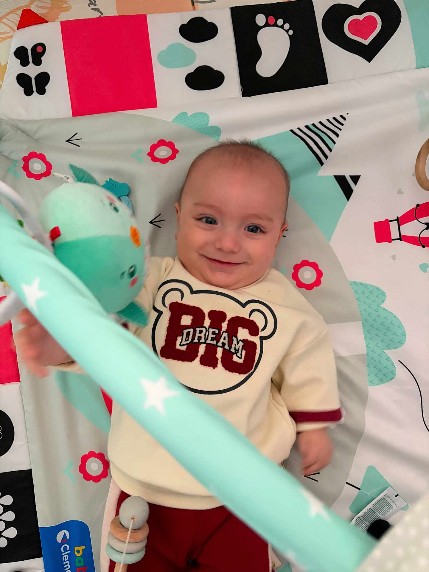 Zahit a rejoint le concours — aidez-le/la à gagner de superbes lots ! baby, infant, smiling, face, eyes, toy, play_mat, plush, onesie, clothing, lying_down, indoor, portrait, happy, hand, pattern, star_pattern, accessory, nursery, cute
