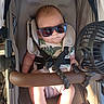 baby, baby_accessory, baby_boy, baby_clothing, casual, child, comfort, cute, fan, head_support, infant, person, portrait, relaxing, seatbelt, shade, stroller, summer, sunglasses, sunlight