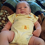 Atlas is registered to the contest to win money with this photo: baby, infant, onesie, blanket, soft, cozy, cartoon_characters, cute, chubby, indoors, furniture, person, child, skin, expression, relaxed, comfort, lying_down, head, arms