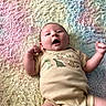 baby, blanket, child, cute, dinosaur, expression, face, fluffy_texture, happy, indoor, infant, lying_down, newborn, onesie, pastel_colors, portrait, raised_arms, skin, smiling, soft_lighting