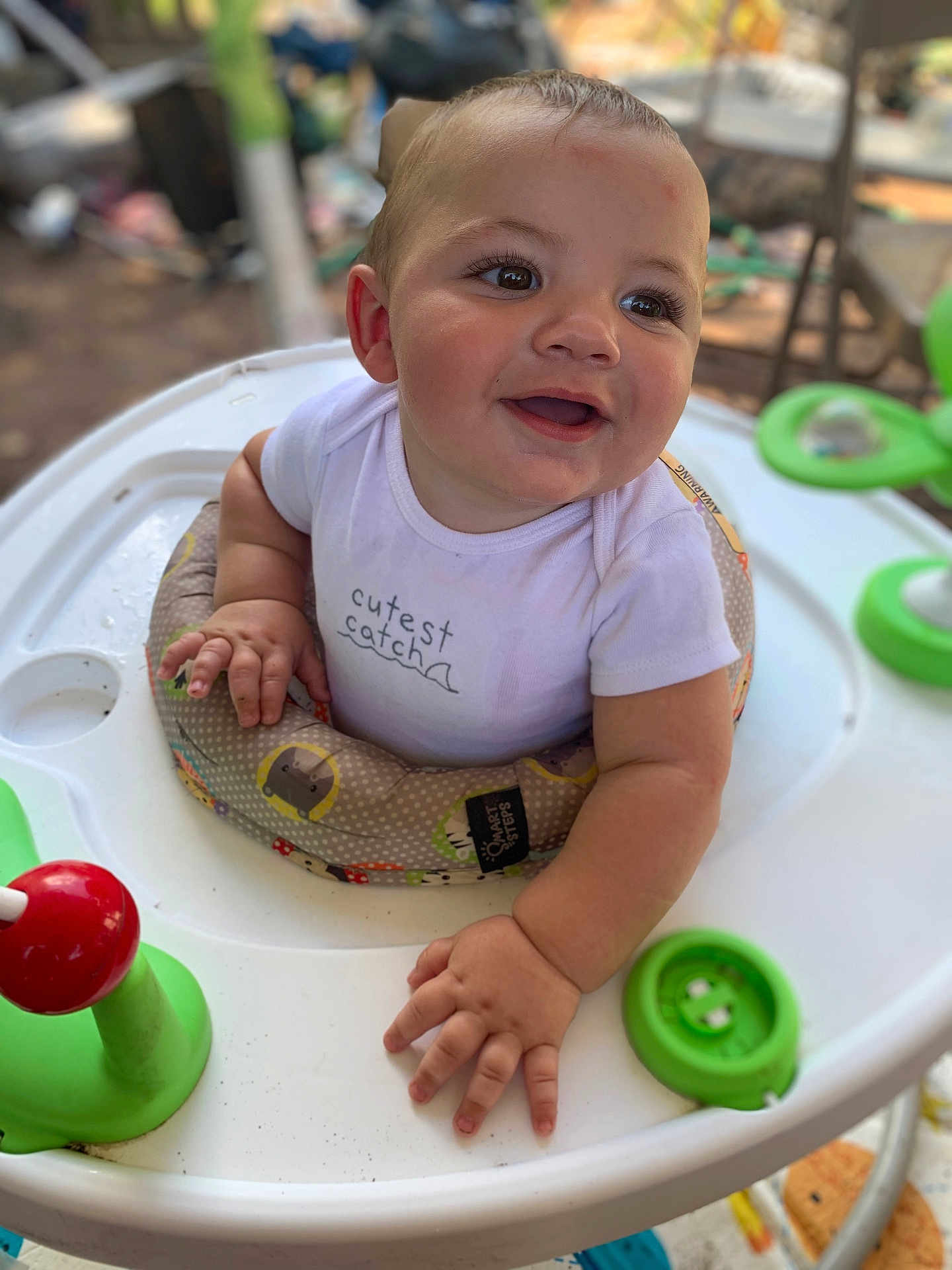 Kane is registered to the contest to win money with this photo: baby, smiling, walker, onesie, child, toy, outdoor, happy, face, hands, seat, infant, cute, playtime, expression, closeup, young, childhood, joy, casual