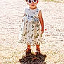 accessory, child, cute, daytime, dress, fashion, footwear, grass, gravel, nature, outdoor, person, playful, shadow, standing, summer, sunglasses, sunlight, toddler, young