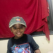 Akheem joined the competition — help win amazing prizes! child, smiling, boy, cap, tshirt, spiderman, indoor, curtain, window, clothing, portrait, happy, person, casual, cute, dark_skin, short_sleeves, standing, fashion, youth