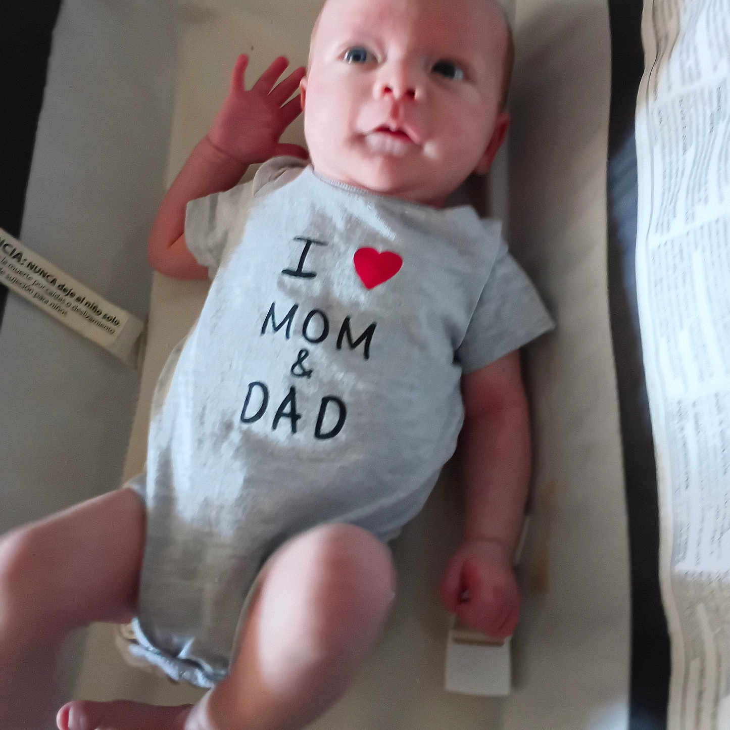 Jax Cane Prater is registered to the contest to win money with this photo: baby, infant, onesie, clothing, crib, bassinet, face, person, child, newborn, cute, lying_down, hand, foot, expression, indoor, fabric, text_on_clothing, love, parental_affection