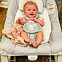 baby, smiling, baby_rocker, blanket, cushion, wooden_floor, infant, happy, clothing, face, feet, person, indoor, seat, head, comfort, cute, child, sitting, expression