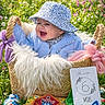 Alba a rejoint le concours — aidez-le/la à gagner de superbes lots ! baby, basket, blue_hat, blue_sweater, child, colorful, cute, floral_pattern, flowers, grass, happy, infant, milestone_card, nature, outdoor, playful, plush, smiling, spring, toys