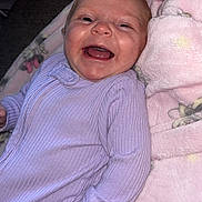 Myla joined the competition — help win amazing prizes! baby, infant, smiling, happy, onesie, purple_clothing, blanket, pink_blanket, floral_pattern, cozy, cute, lying_down, face, skin, child, newborn, portrait, indoor, soft_texture, comfort