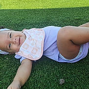 Gracelyn joined the competition — help win amazing prizes! baby, child, grass, headband, smile, outdoor, infant, cute, happy, person, bib, purple_clothing, skin, legs, arm, playing, nature, sunlight, green, lying_down