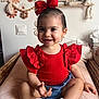 Ava a rejoint le concours — aidez-le/la à gagner de superbes lots ! toddler, child, red_bow, red_top, denim_shorts, white_shoes, smile, face, wicker_basket, indoor, wall_decor, knitted_toys, flower_decor, cute, happy, sitting, baby, earrings, home, portrait