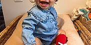 Ava participe au concours pour gagner de l'argent avec cette photo : baby, child, smile, red_bow, red_socks, blue_shirt, sneakers, indoor, changing_pad, wicker_basket, happy, cute, toy, knitted_toy, decor, person, face, sitting, toddler, infant