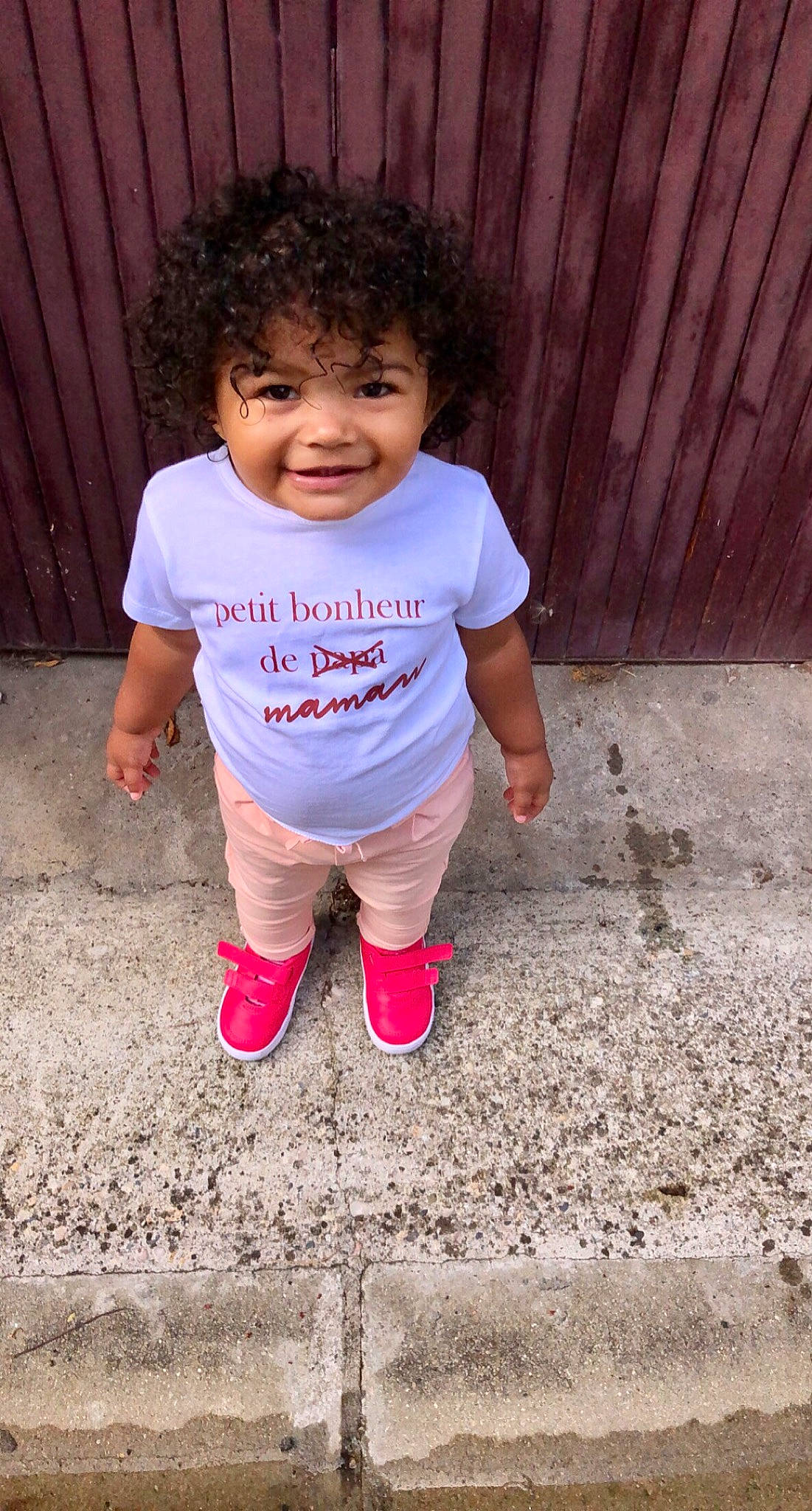 Maïssa participe au concours pour gagner de l'argent avec cette photo : asphalt, baby_toddler_clothing, child, concrete, face, fun, grass, happy, human_leg, leisure, people_in_nature, person, pink, play, road_surface, sitting, sleeve, smile, soil, t_shirt