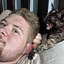 man, face, kitten, cat, tortoiseshell_cat, pet, lying_down, bed, pillow, close_up, young_adult, indoor, animal, feline, beard, hair, expression, resting, cute, playful