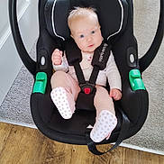 Skyla is registered to the contest to win money with this photo: baby, infant, car_seat, black, pink_clothing, polka_dot_socks, blue_eyes, carrying_handle, flooring, carpet, wood_floor, safety_harness, child, indoor, cute, small, seated, baby_gear, portrait, childcare