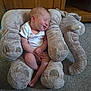 baby, infant, smiling, plush, elephant, stuffed_animal, soft_toy, carpet, wooden_furniture, cozy, indoor, child, white_onesie, cute, sleepy, resting, small, adorable, peaceful, hands
