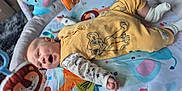 Skyla is registered to the contest to win money with this photo: animal_print, baby, cartoon, child, colorful, cute, elephant_toy, giraffe_toy, happy, indoor, infant, lion_toy, lying_down, play_mat, playtime, smiling, socks, soft_toys, toys, yellow_outfit