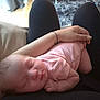 baby, newborn, sleeping, infant, pink_clothing, person, lap, hand, indoor, soft_light, peaceful, relaxation, closeup, human, skin, cuddle, comfort, casual, rest, portrait