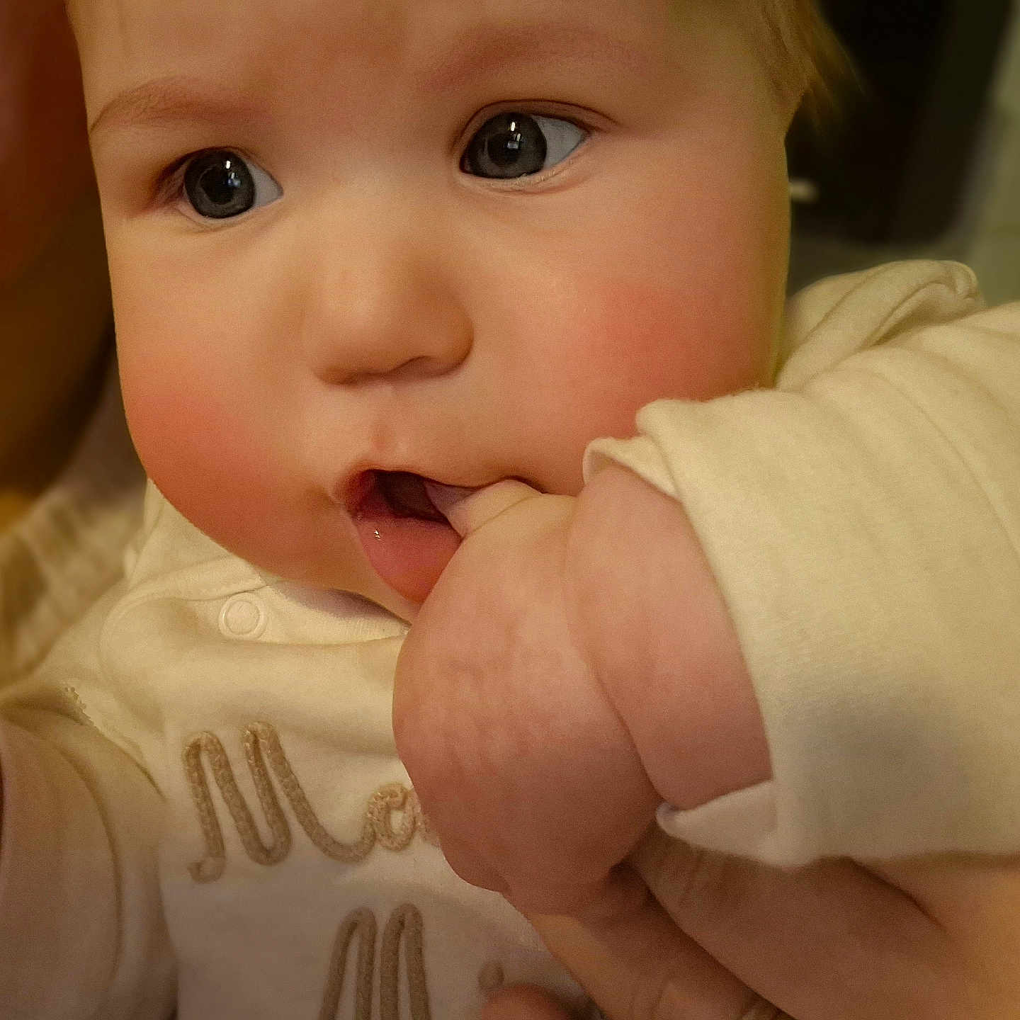 Skyla is registered to the contest to win money with this photo: baby, cheeks, child, close_up, clothing, cream_color, cute, expression, eyes, face, hand, indoor, infant, person, portrait, skin, soft_lighting, sucking, warm, young