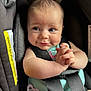 baby, infant, car_seat, safety_harness, pacifier, clothing, cute, chubby_cheeks, expression, face, hands, seat_belt, child, portrait, indoor, smile, skin, human, person, closeup