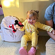 Scotlyn joined the competition — help win amazing prizes! backpack, casual, child, floor, happy, home, indoor, light, minnie_mouse, person, pink_crocs, playful, plush_toy, shadow, sitting, smile, toddler, toy, wall, yellow_clothing