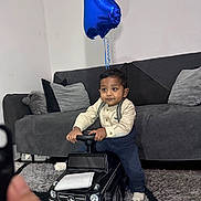 Yaqub joined the competition — help win amazing prizes! toddler, child, toy_car, mercedes, amg, balloon, number_one, living_room, couch, cushion, carpet, indoor, clothing, socks, person, floor, playing, furniture, cute, baby