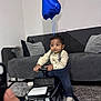 toddler, child, toy_car, mercedes, amg, balloon, number_one, living_room, couch, cushion, carpet, indoor, clothing, socks, person, floor, playing, furniture, cute, baby
