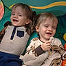 children, toddlers, twins, siblings, smiling, laughing, faces, indoor, play_tent, playroom, dinosaur, pajamas, clothing, toys, toy_balls, seated, portrait, happy, colorful, candid