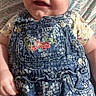 baby, smiling, head_wrap, denim, overalls, floral_pattern, infant, cute, happy, child, portrait, clothing, baby_girl, fabric, person, sitting, casual, indoor, pattern, background