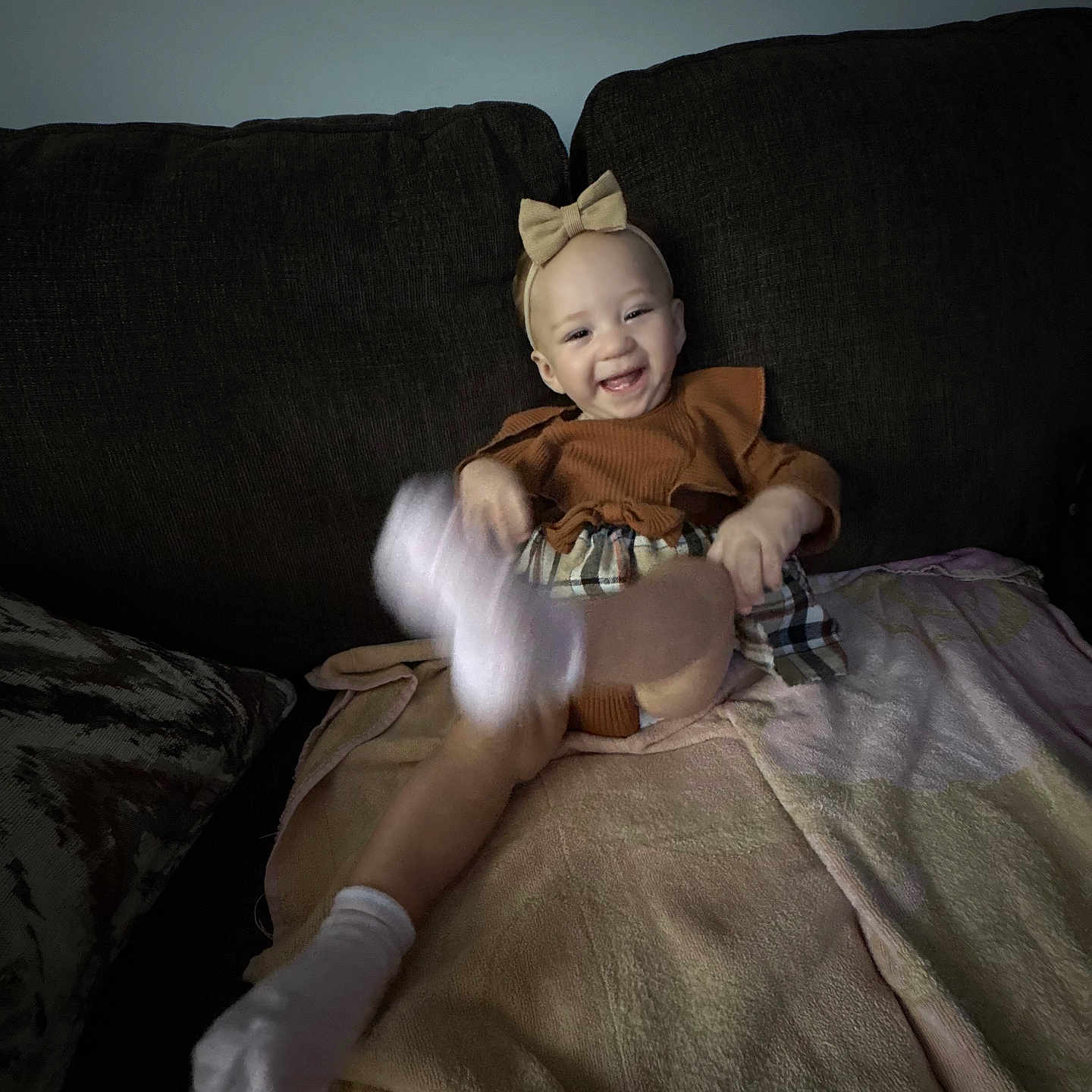 Melainee joined the competition — help win amazing prizes! baby, blanket, bow, brown_outfit, child, couch, furniture, happy, headband, home, indoor, infant, kicking, motion_blur, plaid_skirt, portrait, sitting, smiling, socks, soft_lighting