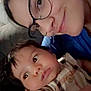 Chance is registered to the contest to win money with this photo: baby, person, glasses, face, indoor, plaid, clothing, child, portrait, smile, holding, curious, closeup, adult, candid, skin, head, expression, casual, family