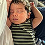 baby, sleeping, infant, striped_clothing, arm_raised, couch, blanket, indoor, closeup, peaceful, child, person, relaxing, soft_lighting, cozy, hair, face, head, resting, casual