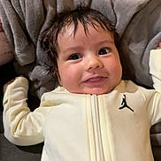 Chance joined the competition — help win amazing prizes! baby, infant, smile, face, eyes, hair, blanket, clothing, zipper, logo, soft_texture, indoor, cute, happy, person, portrait, lying_down, warm, cozy, child