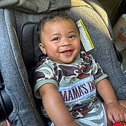 Princeton is registered to the contest to win money with this photo: baby, camouflage, car_seat, caterpillar_toy, child, clothing, cute, face, hand, happy, head, indoors, infant, person, portrait, seat, sitting, smiling, sunlight, toy