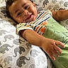 Princeton is registered to the contest to win money with this photo: baby, smiling, infant, pillow, elephant_pattern, striped_clothing, green_outfit, reaching_hand, happy, cute, indoor, floor, toy, plush, child, portrait, lying_down, cozy, warm, soft
