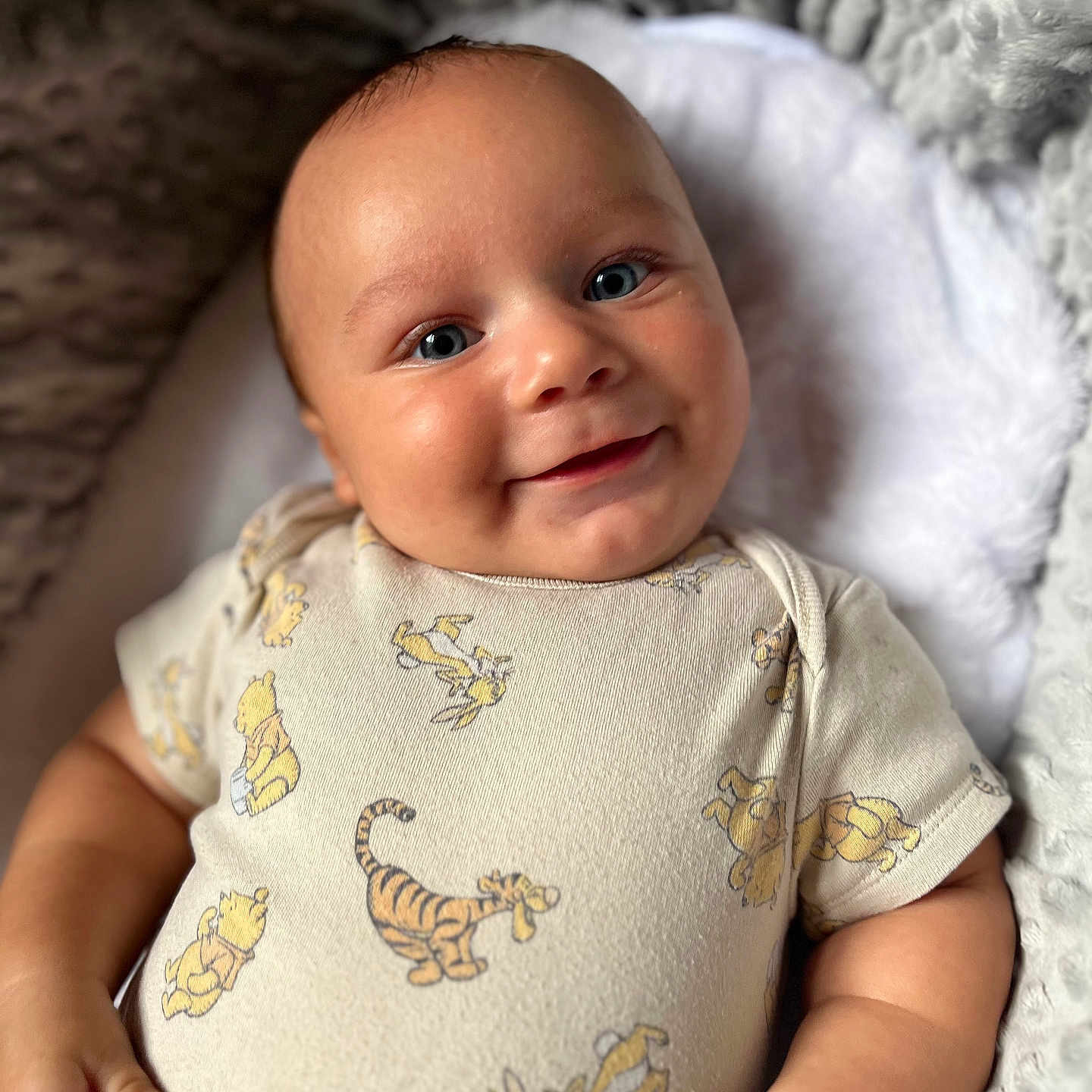 Taio is registered to the contest to win money with this photo: baby, blanket, blue_eyes, child, close_up, comfortable, cozy, cute, hand, happy, infant, lying_down, onesie, portrait, rabbit, skin, smile, soft_texture, tiger, winnie_the_pooh