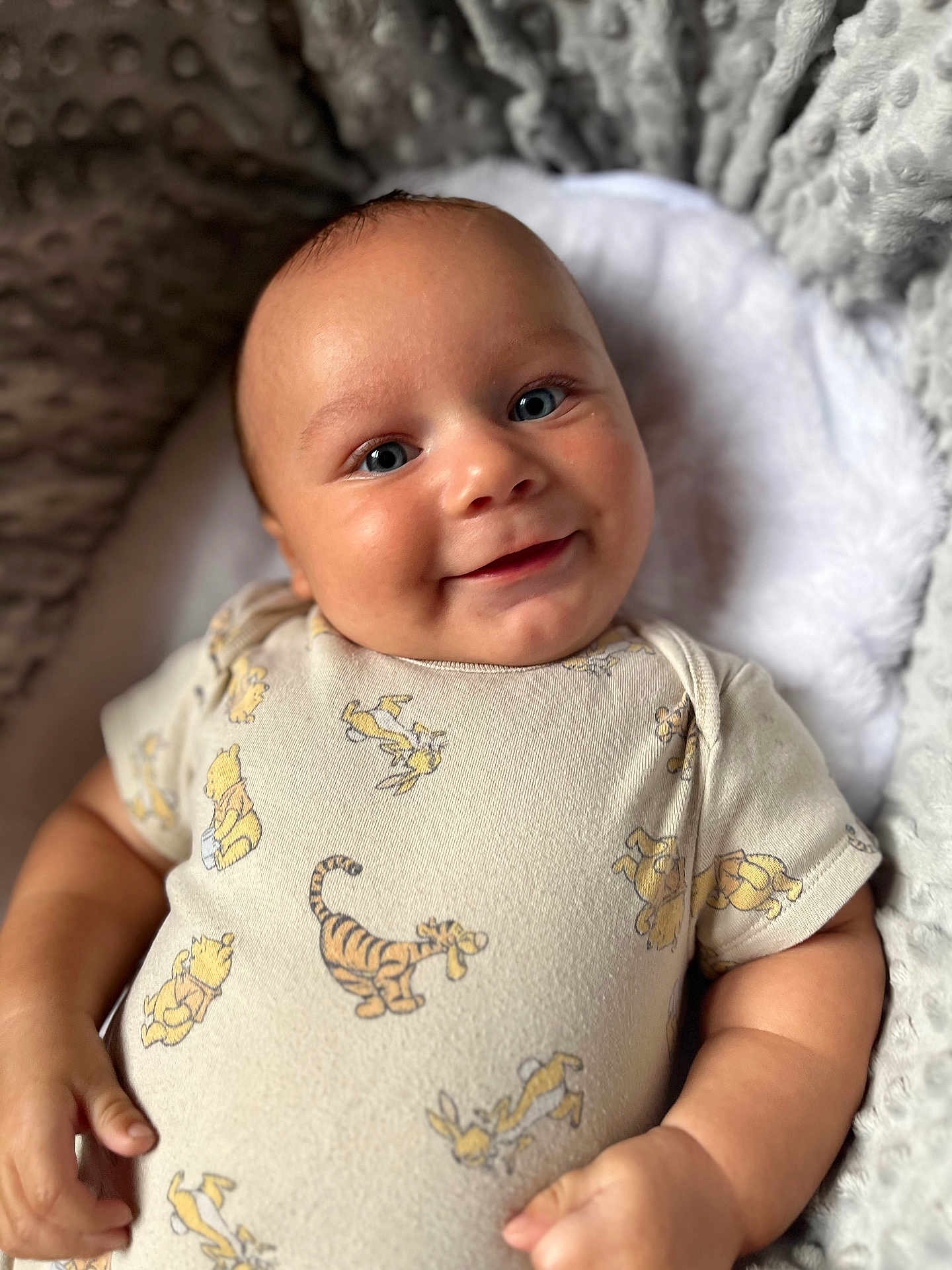 Taio is registered to the contest to win money with this photo: baby, blanket, blue_eyes, child, close_up, comfortable, cozy, cute, hand, happy, infant, lying_down, onesie, portrait, rabbit, skin, smile, soft_texture, tiger, winnie_the_pooh