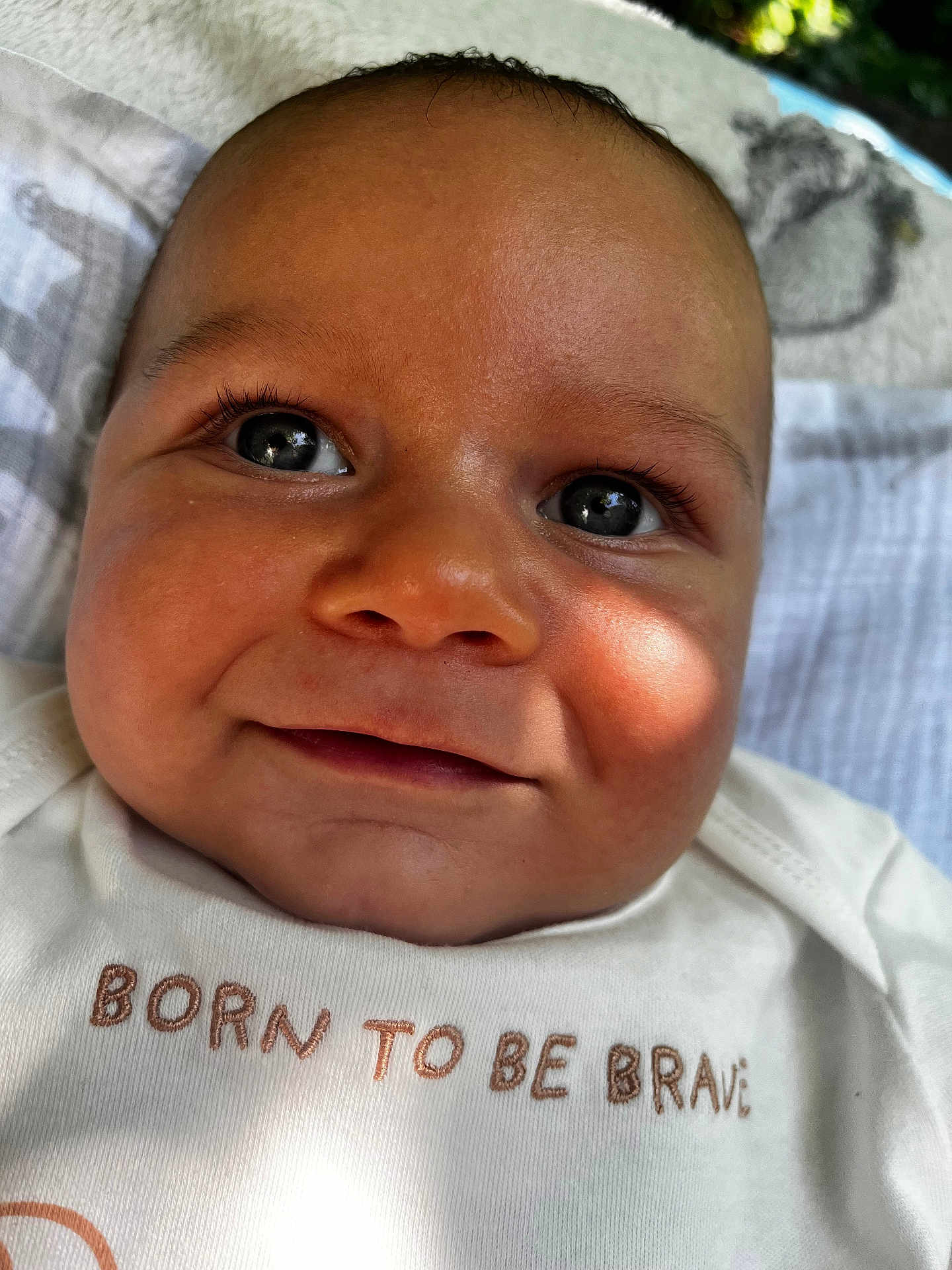 Taio joined the competition — help win amazing prizes! baby, close_up, face, smile, eyes, infant, child, cute, white_shirt, text_on_clothing, blanket, soft_light, indoors, portrait, happy, young_child, skin, head, expression, human