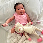 Lariany is registered to the contest to win money with this photo: baby, infant, pink_dress, stuffed_animal, pacifier, white_bed, blanket, socks, cute, smiling, indoors, soft_toy, baby_girl, resting, cozy, child, portrait, comfort, sleepwear, happy
