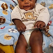 Aurthor is registered to the contest to win money with this photo: baby, infant, smiling, face, blanket, teddy_bear, clothing, diaper, feet, hands, cute, indoors, child, happy, portrait, soft_texture, sports_pattern, cozy, laying_down, young