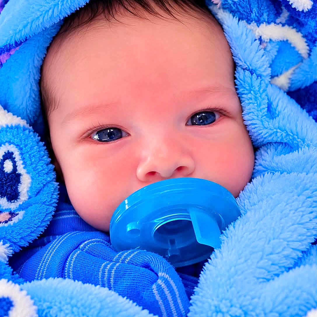Cristopher joined the competition — help win amazing prizes! baby, infant, child, portrait, face, blue_blanket, pacifier, wide_eyes, indoors, close_up, sleepwear, wrapped, cozy, soft_texture, head, eyes, nose, mouth, blue, photography