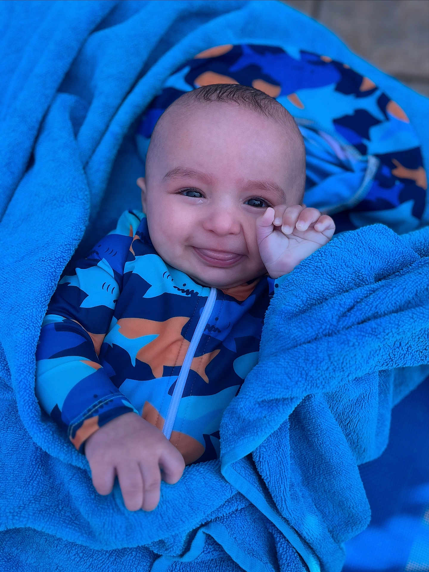Nassim participe au concours pour gagner de l'argent avec cette photo : baby, child, towel, blue, smile, face, hand, clothing, patterned_outfit, shark_pattern, infant, cute, wrapped, portrait, happy, skin, playful, young, person, indoors